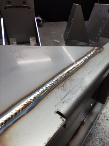 Ein geschweißter Metallstreifen mit farbigen Verfärbungen auf der Oberfläche.