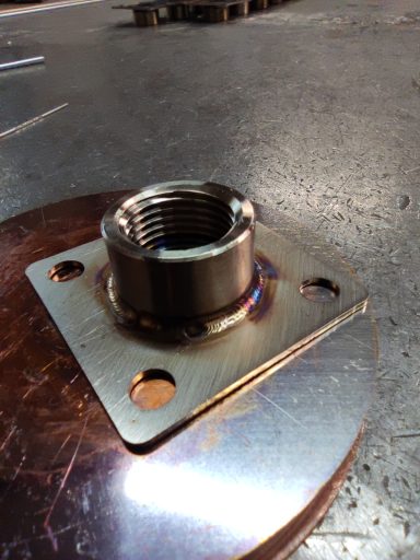 Metallplatte mit einer Gewindebuchse und vier Befestigungslöchern.
