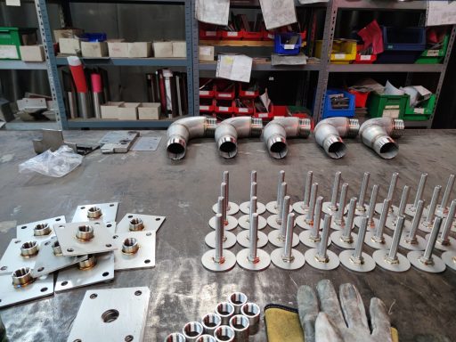 Rohrfittings, Schrauben und Material in einer Werkstattansicht auf einem Arbeitstisch.