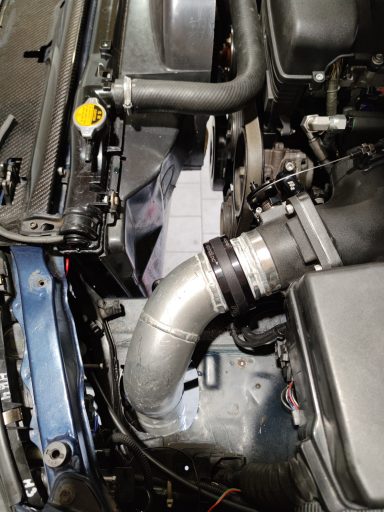 Motorraum mit Kühlerschlauch und Metallrohrverbindung.
