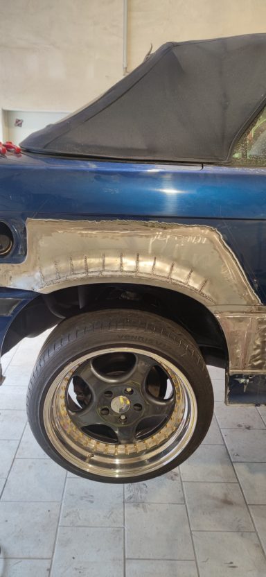 Blaues Auto mit modifiziertem Kotflügel und sportlichem Rad.