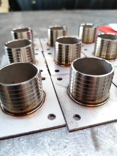 Mehrere Flanschplatten mit Stutzen auf einer Werkbank.